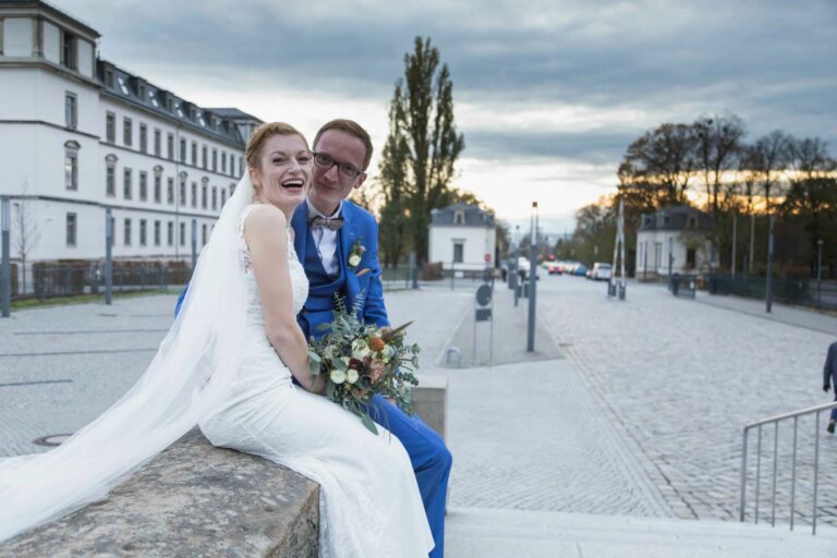 Brautpaar sitzt zusammen und schauen in die Kamera des Fotografen Möbeln