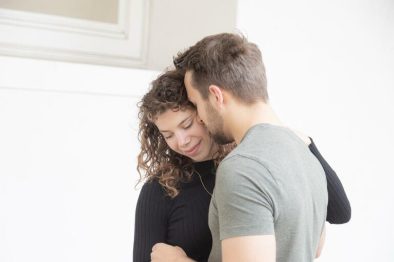 Foto-Shooting eines Paares. der Freund küsst seine Freundin liebevoll und sie streicheln sich zärtlich. Das Paar zeigt seine Liebe zu einander in der Öffentlichkeit. Natürliche und authentische Bilder die außerhalb des Studio entstehen.