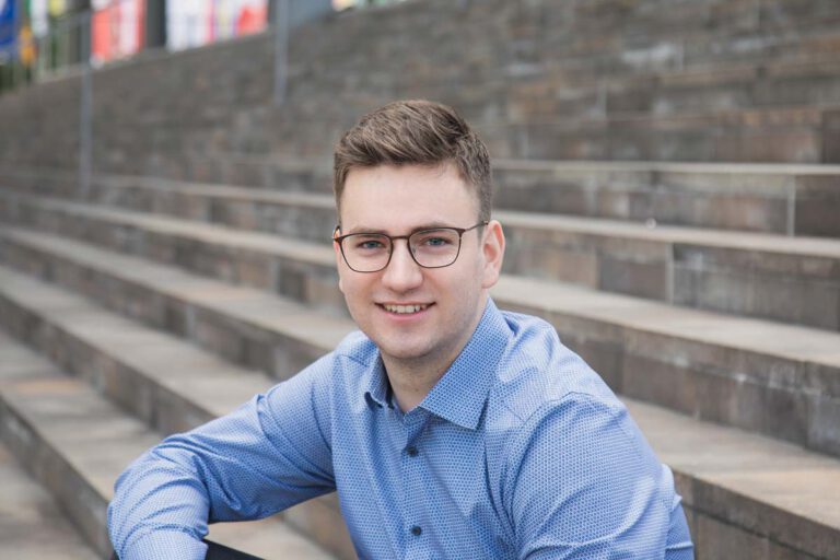 Bewerbungsfoto eines jungen Mannes auf einer Treppe in Dresden. Natürliches und modernes Bewerbungsfoto für deine Bewerbung.