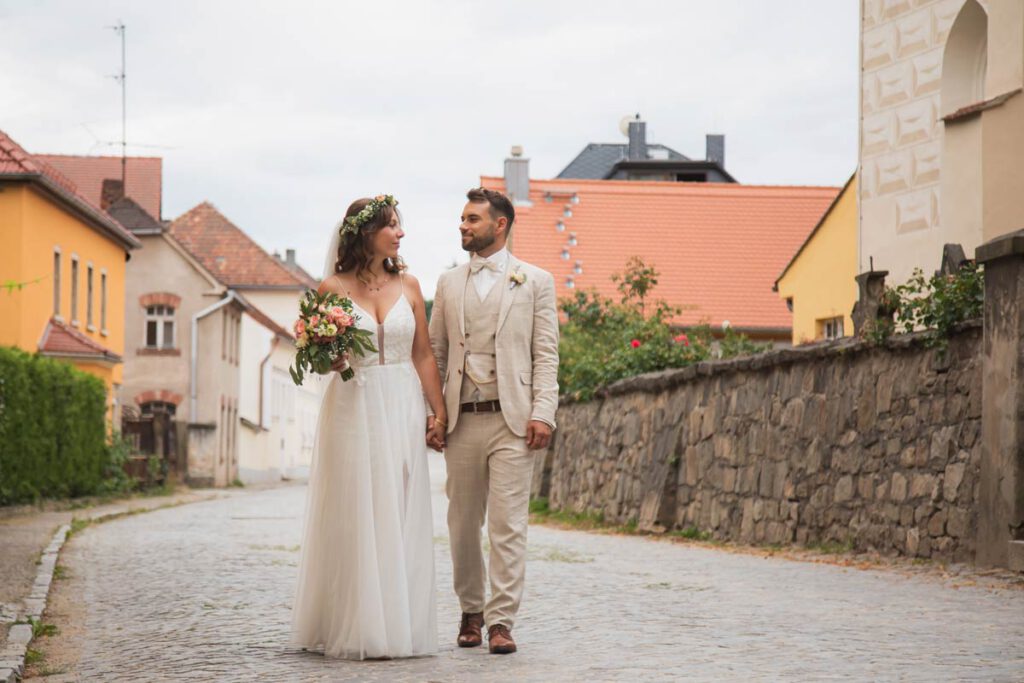 Brautpaarfotos in Bautzen - Paar schaut sich verliebt an und geht eine Straße entlang